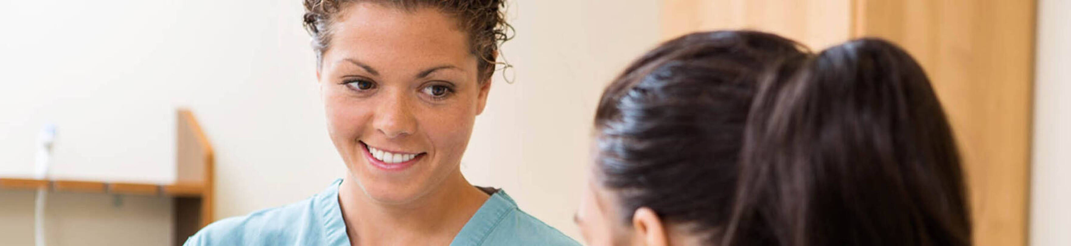Image of a Clinical Medical Assistant in scrubs working with a patient