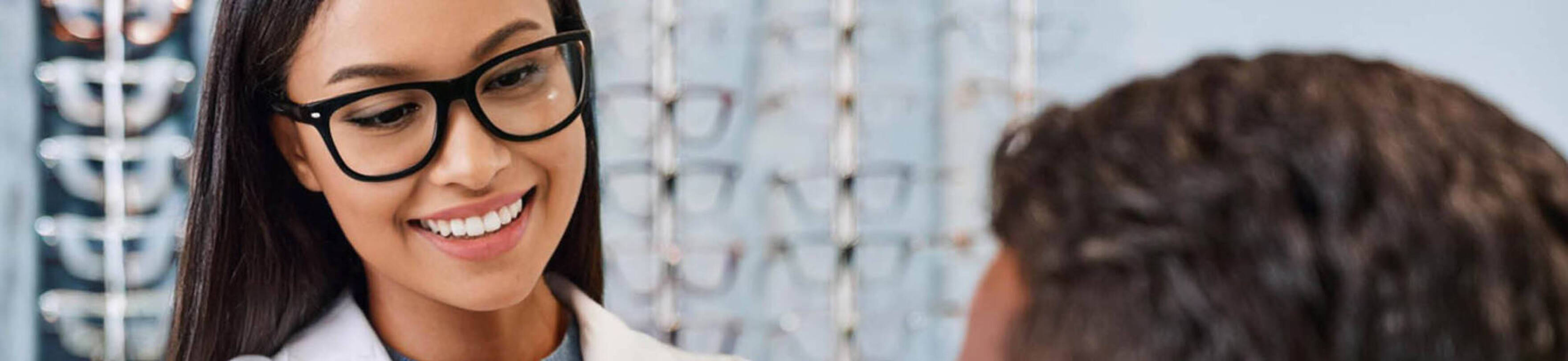 Image of an optician assisting a patient in trying on glasses